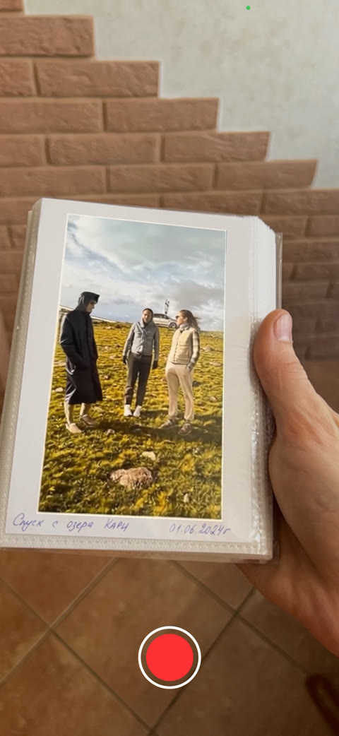 Lifoto's camera view: a hand holds an open photo album, and the print inside it is already playing as video